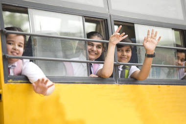 快樂(lè)的小學(xué)生從校車的窗戶揮手
