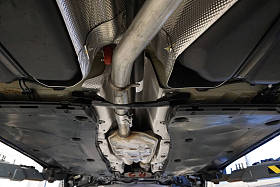 锐利的技术照片。现代汽车的设计和元素。排气系统的详细信息。排气管。中间管道。消声器。舍身底部