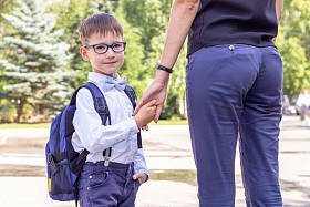 这个男孩是一个戴着眼镜的一年级学生,手里拿着一个蓝色的公文包