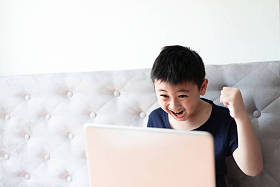 小男孩使用笔记本电脑玩游戏在家里放松
