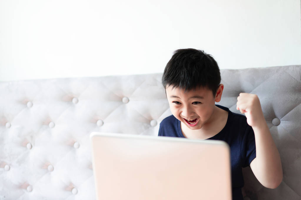小男孩使用笔记本电脑玩游戏在家里放松