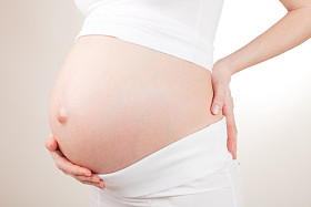 怀孕的女人着她的肚子手臂照片