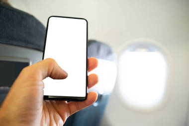 在飛機上用手機與空白屏幕的人的手的特寫
