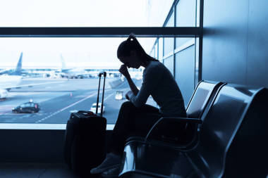壓力的女人在機場拿著智能手機. 