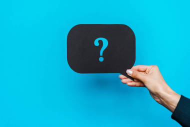 裁剪視圖的婦女拿著黑色語(yǔ)音氣泡與藍(lán)色問(wèn)號(hào)