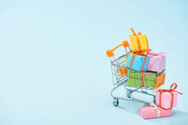 節(jié)日包裝的禮物在藍(lán)色背景的購物車與復(fù)制空間