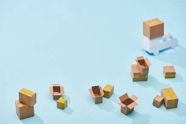 藍(lán)色背景上迷你卡車附近的分散紙板箱，帶有復(fù)制空間