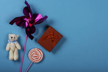 风车，泰迪熊，棒棒糖和蓝色背景的礼物。图像右侧的文本空间