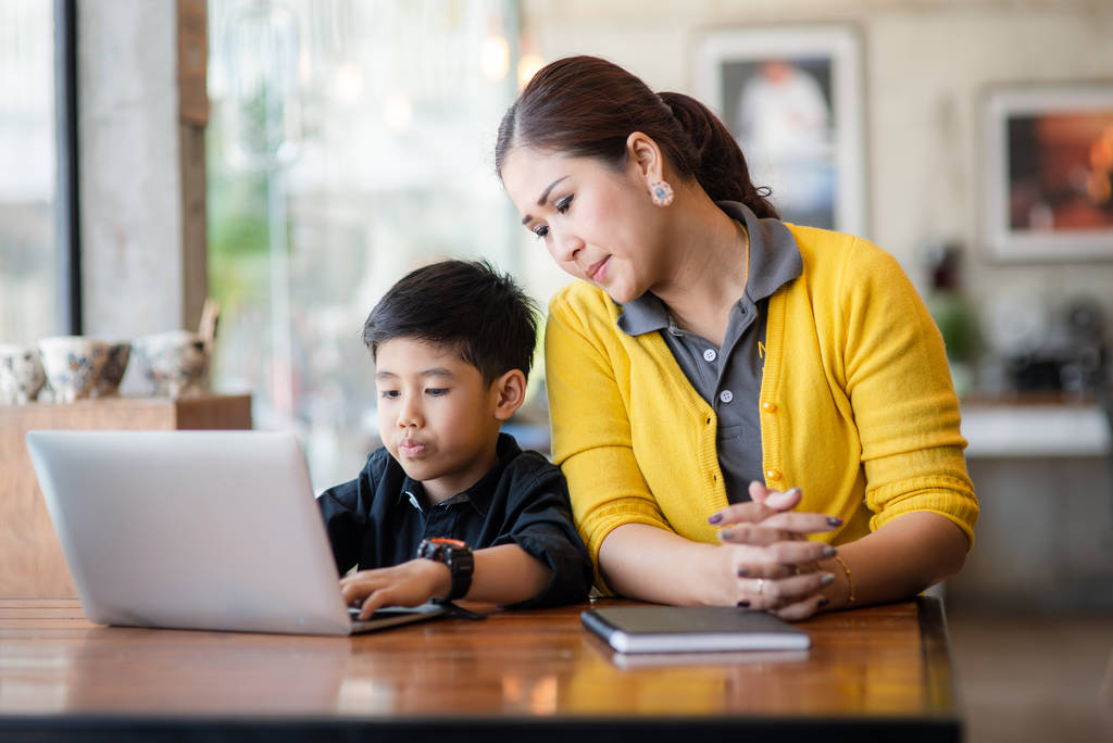 快乐的亚洲母亲和她的儿子在家里使用笔记本电脑 快乐的亚洲母亲和她的儿子在家里使用笔记本电脑