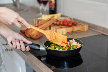 女孩在爐子上煮蔬菜，用木鏟攪