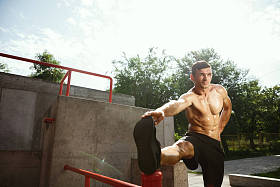 年轻的肌肉男子，而做他的锻炼在操场外