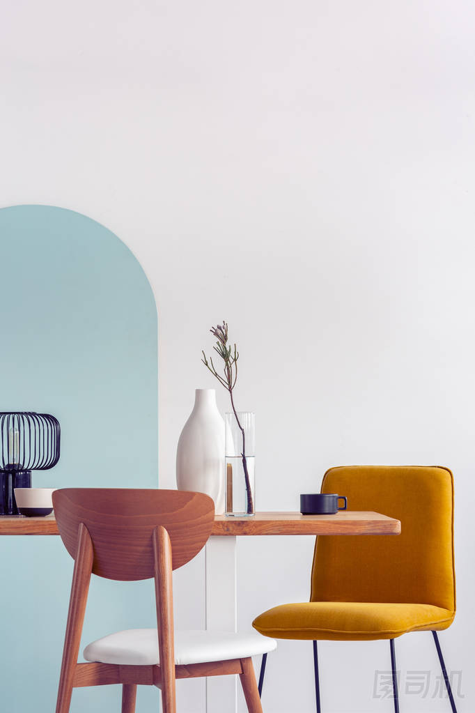 木桌上的白色花瓶，有花哨的用餐室內(nèi)部，有白色和藍(lán)色墻