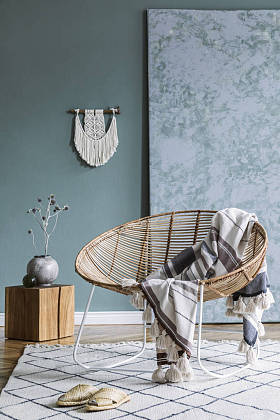 时尚的简约客厅内部，配有设计藤式扶手椅和优雅的配饰。墙的紫杉颜色。复制空间