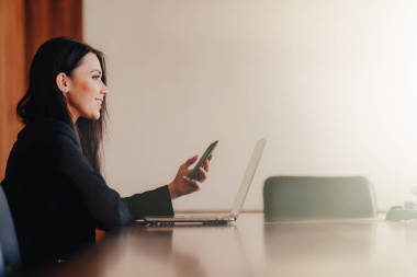 年轻迷人的情感女孩，穿着商务风格的衣服，坐在办公室或礼堂的笔记本电脑和电话的办公桌上