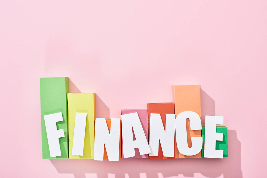 粉红色背景上彩色块图上方的财务铭文顶部视图 粉红色背景上彩色块图上方的财务铭文顶部视图