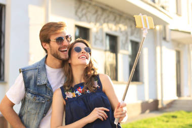 美丽可爱的年轻夫妇在城市街道上散步，一边拥抱一边自拍