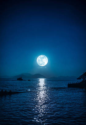夜间和月亮在平静的海水中欣赏小船的风景