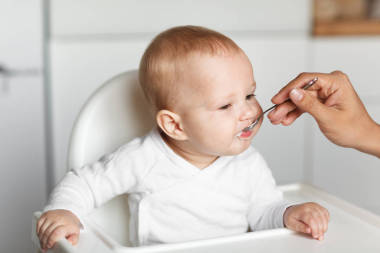 在厨房用勺子喂养可爱的婴儿图片