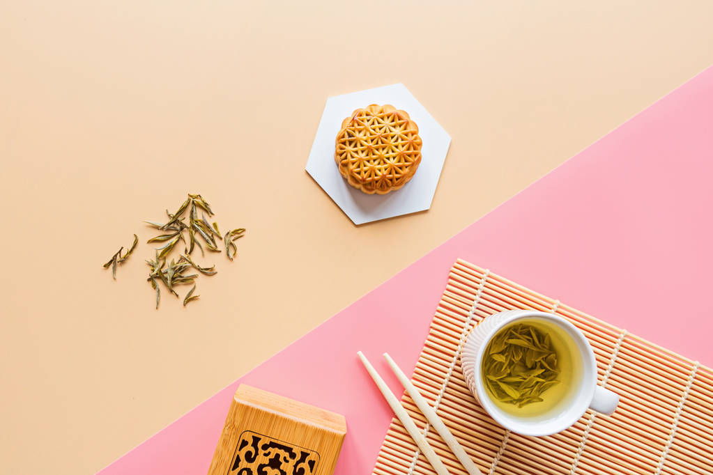 平铺中秋节甜点，中秋节月饼，背景五彩斑斓，绿茶和筷子。 顶部视图、复制空间、模型、头顶、模板