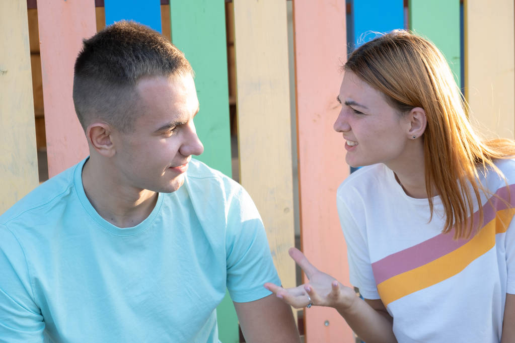 年轻夫妇在户外争吵。红发女孩对她的男孩很生气 年轻夫妇在户外争吵。红发女孩对她的男孩很生气