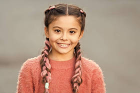 女孩与可爱的脸微笑在户外。美丽的发型。时尚的发型为孩子们。小女孩与时尚辫子发型。时尚潮流。沙龙和护发。辫子发型