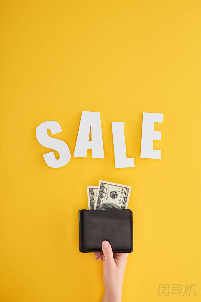 部分觀點的婦女持有錢包與美元的黃色背景與銷售的字母
