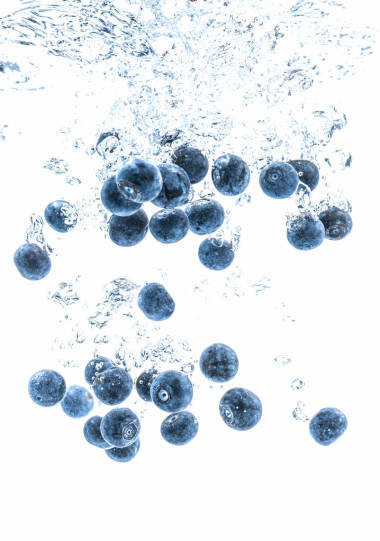 新鮮的藍(lán)莓掉進(jìn)水里的白色背景。水果濺入清水