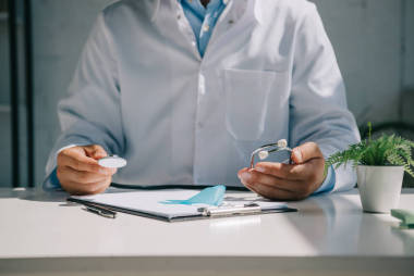 醫(yī)生坐在辦公桌前，手持聽診器靠近藍色感知帶的剪影