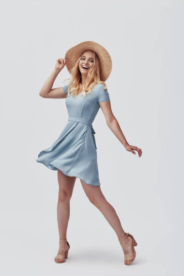 全長有吸引力的年輕女子看著相機(jī)和微笑,而站在灰色的背景 