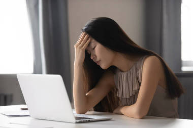 長期使用筆記本電腦后頭痛的疲憊的亞洲女商人