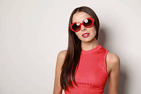 漂亮的女人，戴着时髦的太阳镜，浅色背景，文字空间