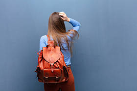 年轻漂亮的女人靠着蓝色的墙，有一个复制的空间