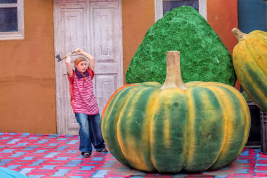 一個(gè)小玩具男孩用斧頭砍南瓜的滑稽圖片