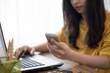 使用智能手機和筆記本電腦在家工作的年輕女子 