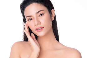 美丽的年轻亚洲女人，用清澈的肌肤触摸着柔软的面颊微笑幸福而快乐，被白色的背景、美感和美感所隔离