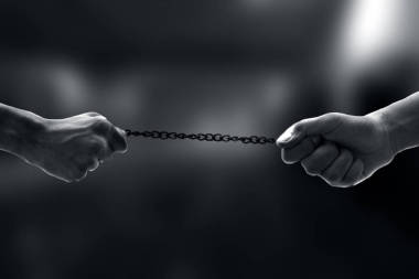 在辦公室停車場(chǎng)的公司部門背景模糊不清的情況下，這對(duì)手拉著生銹的金屬鏈條進(jìn)行拉鋸戰(zhàn)的親密鏡頭