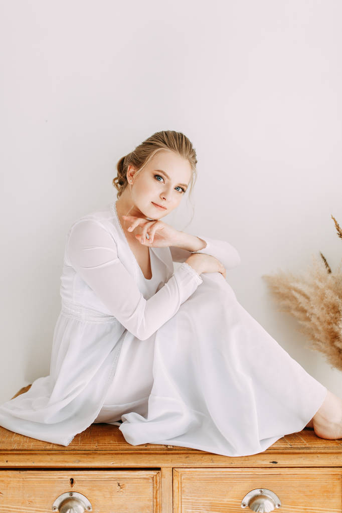 穿着欧洲风格的闺房服装的女孩。 早上新娘在室内工作室.  穿着欧洲风格的闺房服装的女孩。 早上新娘在室内工作室.