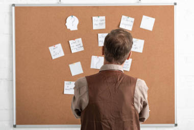 一個身患重病的老人站在木板邊，手里拿著文件的倒影 