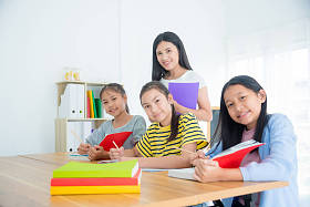 三个亚洲学生在教室里坐着看书 