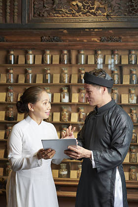 亚洲老药店的药剂师在平板电脑上向同事们展示信息，并为他安排当天的工作