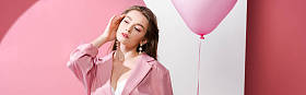 迷人的年轻女子拿着粉色和白色气球的全景照