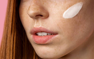 年轻美丽的姜汁女人脸上涂满了奶油