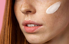 年轻美丽的姜汁女人脸上涂满了奶油