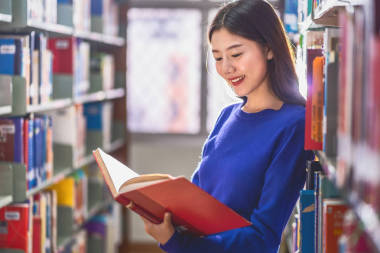 亞洲青年學(xué)生身著休閑服，在大學(xué)圖書館的書架上看書，或以各種書本背景，回到學(xué)校概念