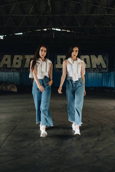 穿著牛仔褲和白色T恤的兩個年輕的布魯內(nèi)特孿生姐妹的肖像，在賽馬場上擺姿勢