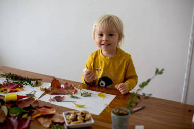 可愛的孩子，蹣跚學(xué)步的男孩，用膠水涂樹葉