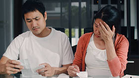 年轻的亚洲怀孕夫妇记录收入和开支在家里。妈妈担心，严重，压力，而记录预算，税收，财务文件工作在客厅在家里的概念