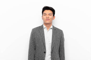 年輕的中國(guó)男子面帶微笑，面帶微笑，面帶微笑地看著你，用積極的態(tài)度面對(duì)著平坦的彩墻