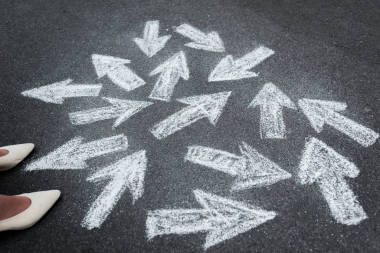 婦女站在瀝青路面上的近向箭頭的剪影 