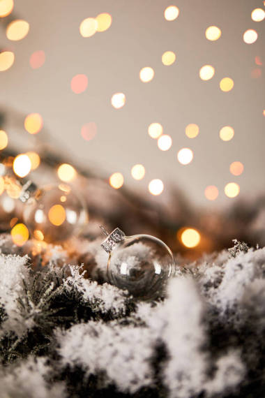 雪中的云杉樹枝上的透明的圣誕球，黃燈模糊